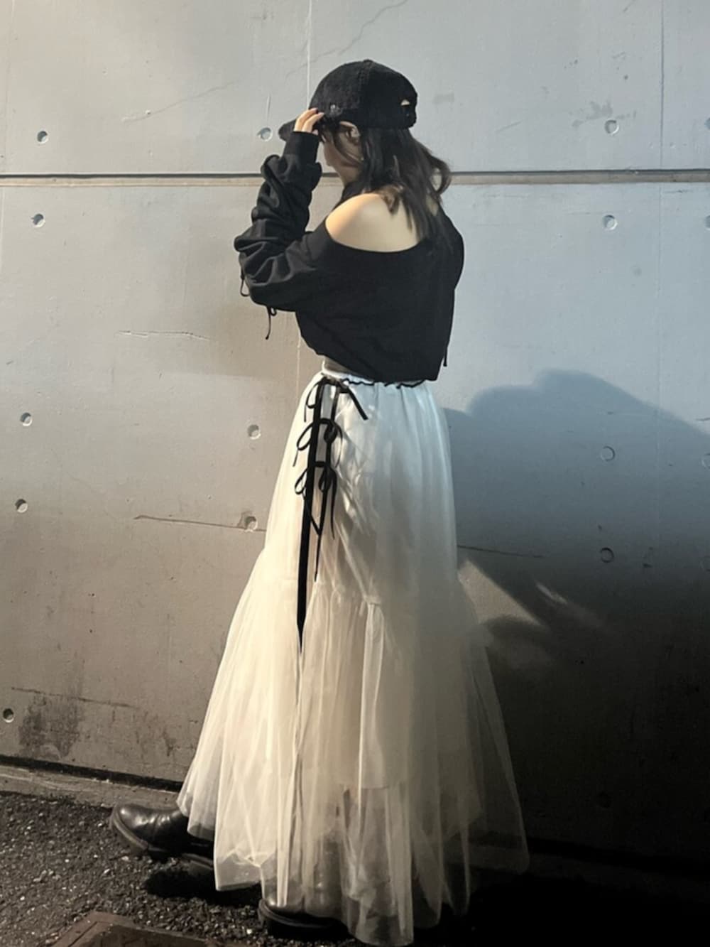 ブラック系のスウェット、ホワイト系のスカート、ブラック系のキャップを着用したレディースの秋コーディネートの2枚目の写真