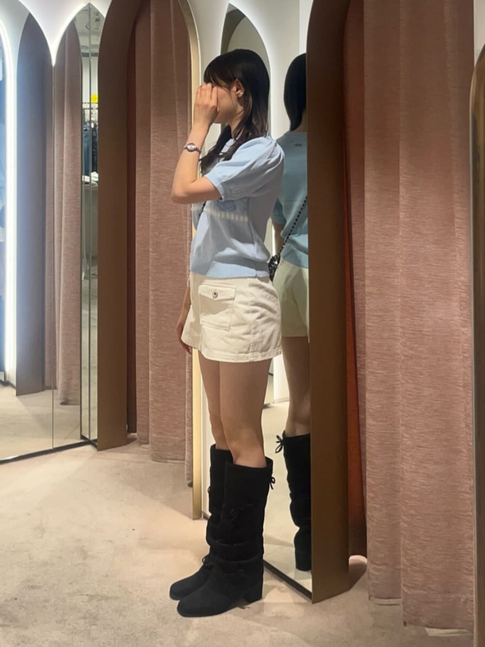 ホワイト系のスカート、ブラック系のブーツ、ブルー系のニット/セーターを着用したレディースの夏コーディネートの2枚目の写真