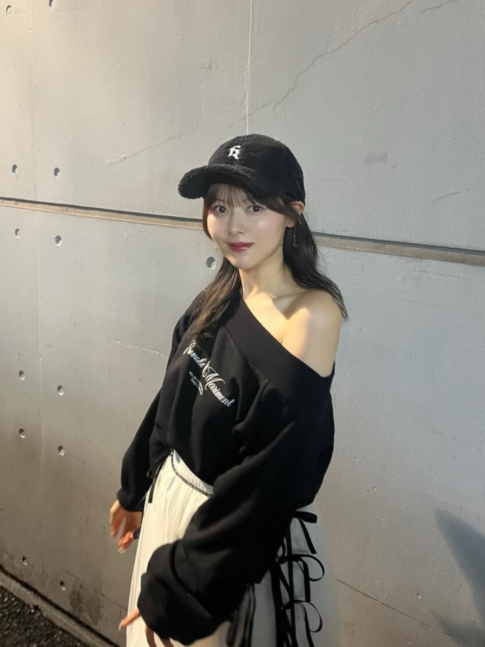 ブラック系のスウェット、ホワイト系のスカート、ブラック系のキャップを着用したレディースの秋コーディネートの4枚目の写真