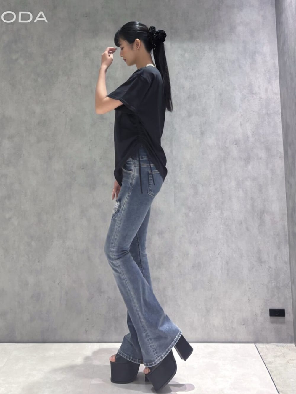 ブルー系のデニムパンツ、ブラック系のサンダル、ブラック系のTシャツ/カットソーを着用したレディースの春コーディネートの3枚目の写真
