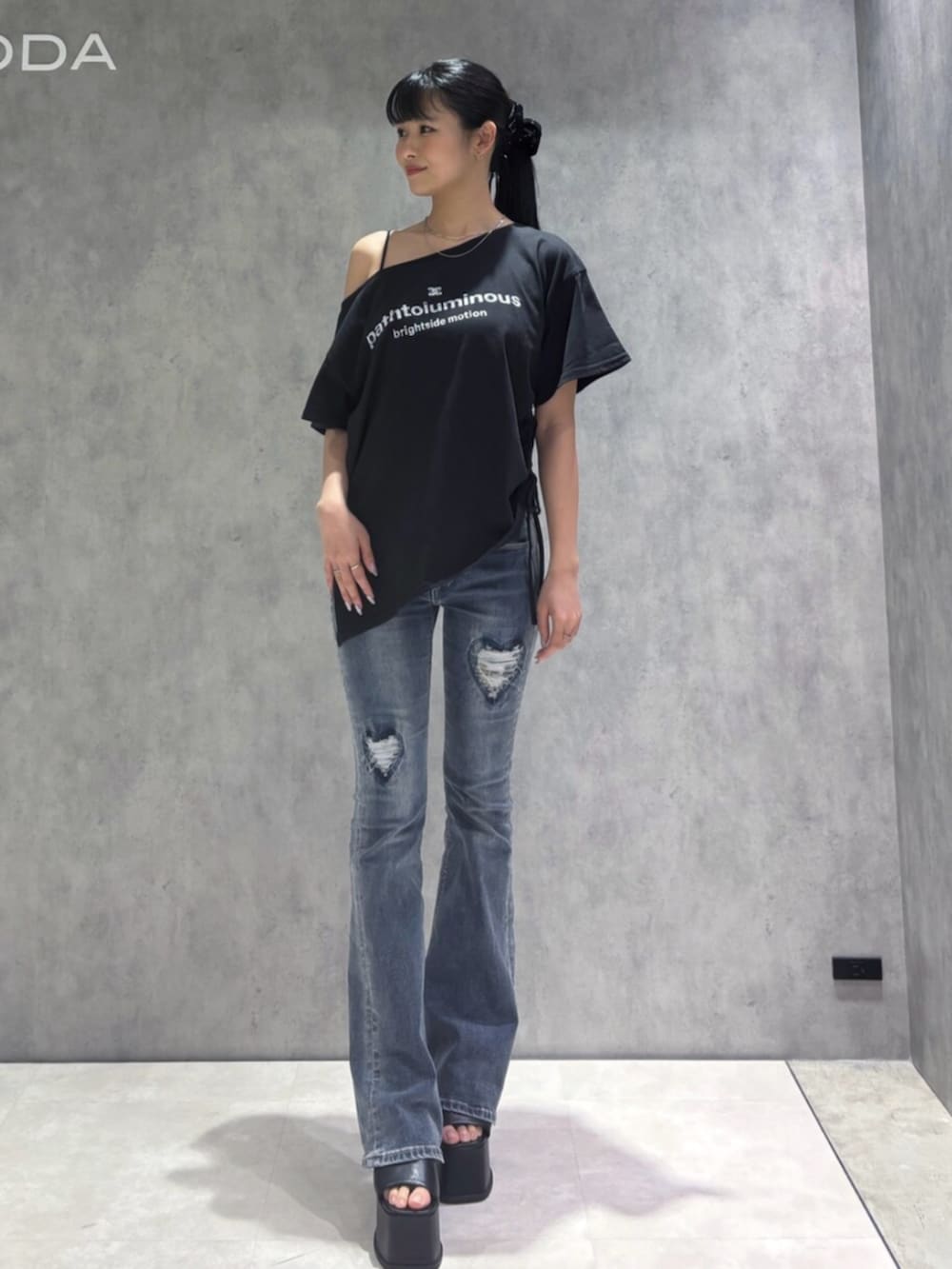 ブルー系のデニムパンツ、ブラック系のサンダル、ブラック系のTシャツ/カットソーを着用したレディースの春コーディネートの2枚目の写真