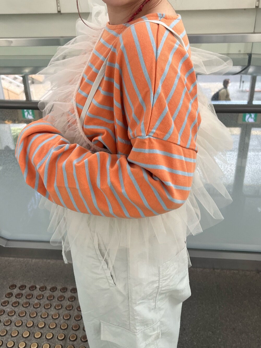 グレー系のサロペット/オーバーオール、ベージュ系のベスト、オレンジ系のTシャツ/カットソーを着用したレディースの冬コーディネートの7枚目の写真