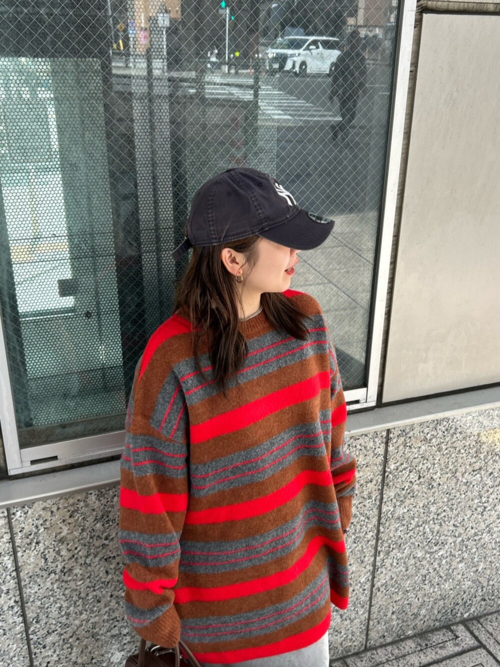 グレー系のスカート、レッド系のニット/セーター、ブラウン系のハンドバッグを着用したレディースの秋コーディネートの4枚目の写真