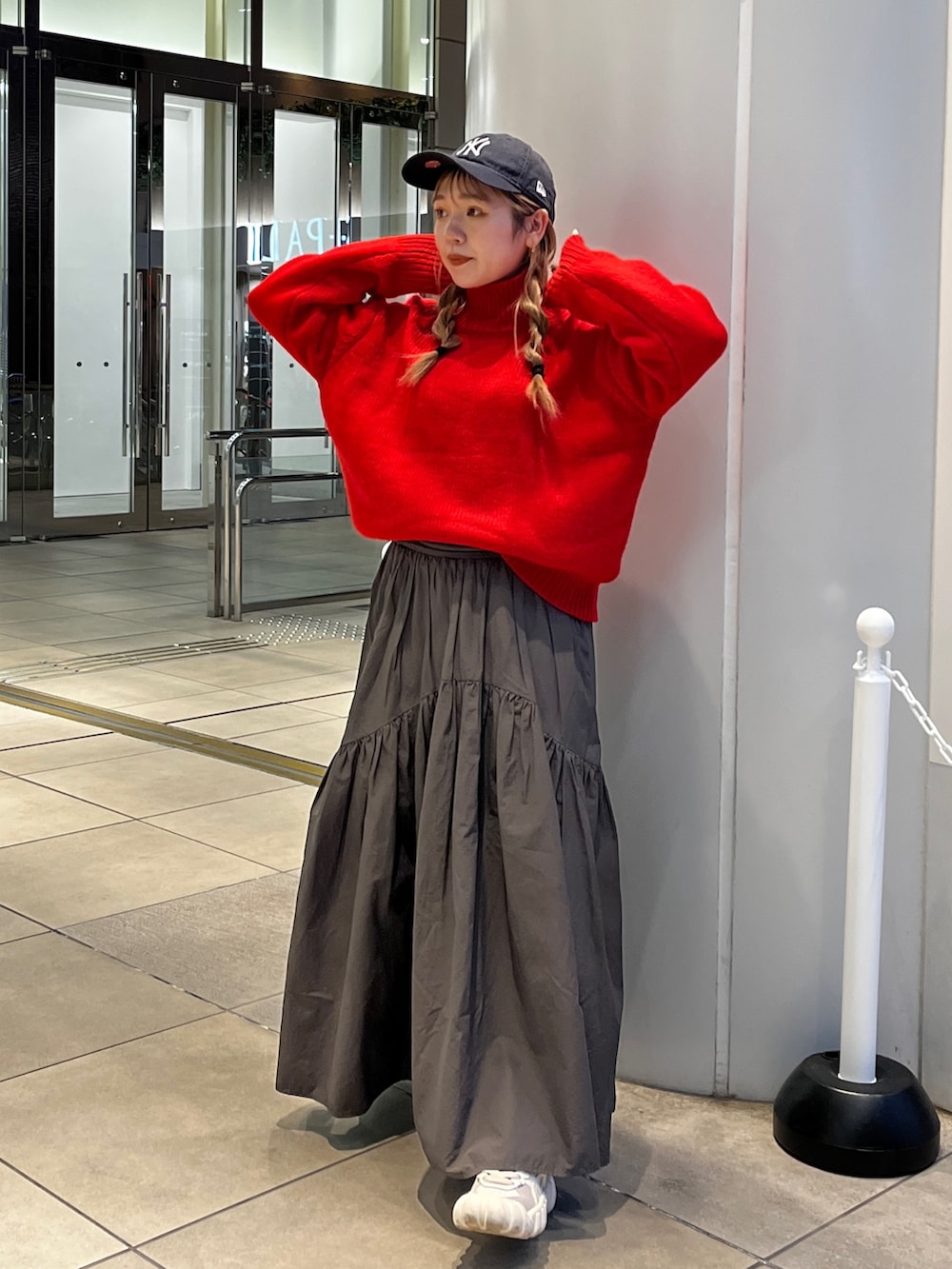 レッド系のニット/セーター、グレー系のスカートを着用したレディースの秋コーディネートの2枚目の写真