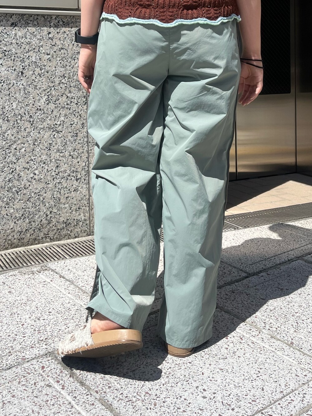 グリーン系のその他パンツ、ブラウン系のニット/セーター、ホワイト系のキャミソールを着用したレディースの春コーディネートの7枚目の写真