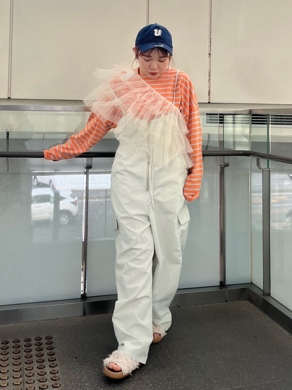 グレー系のサロペット/オーバーオール、ベージュ系のベスト、オレンジ系のTシャツ/カットソーを着用したレディースの冬コーディネートの2枚目の写真