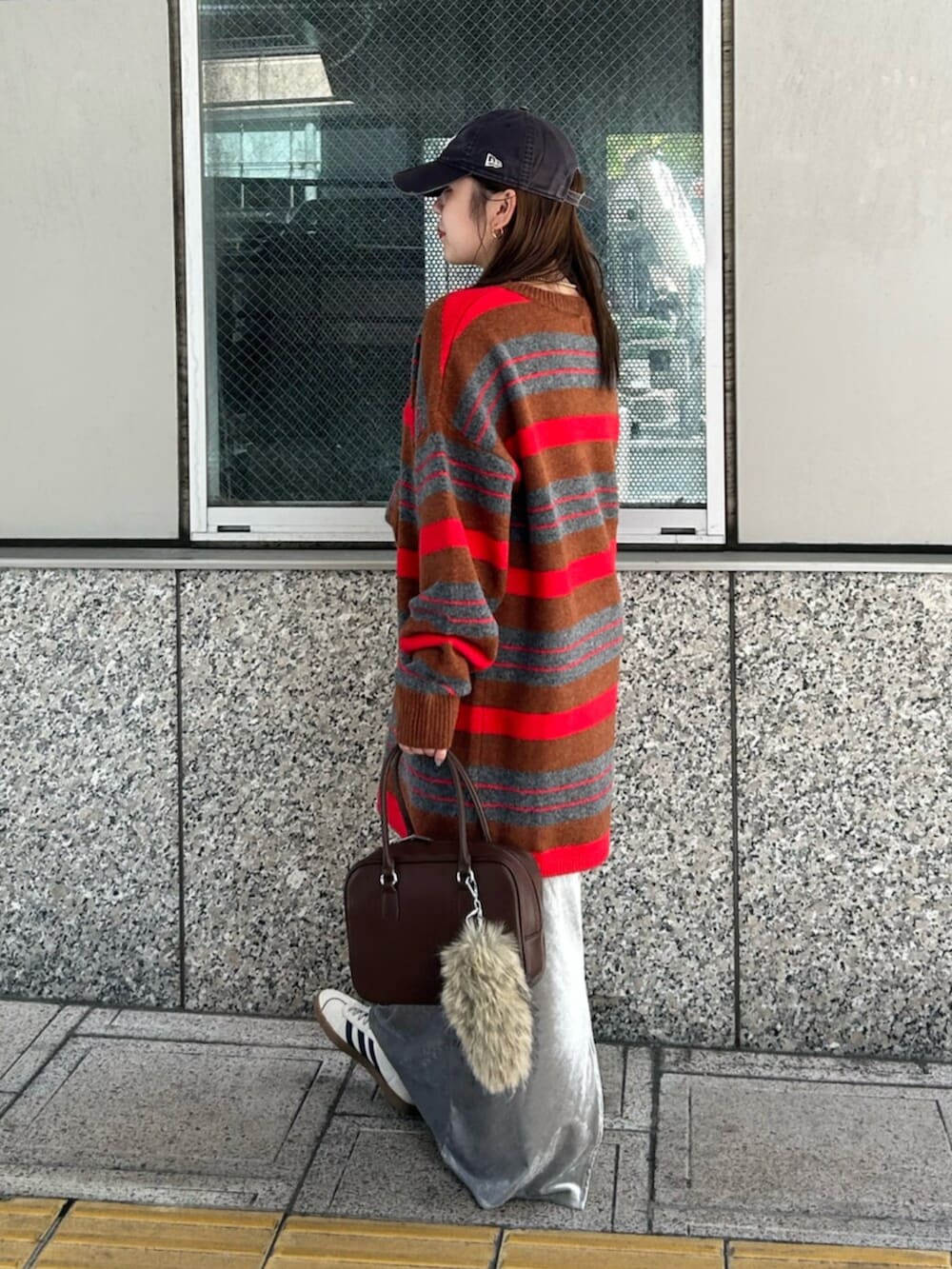 グレー系のスカート、レッド系のニット/セーター、ブラウン系のハンドバッグを着用したレディースの秋コーディネートの2枚目の写真
