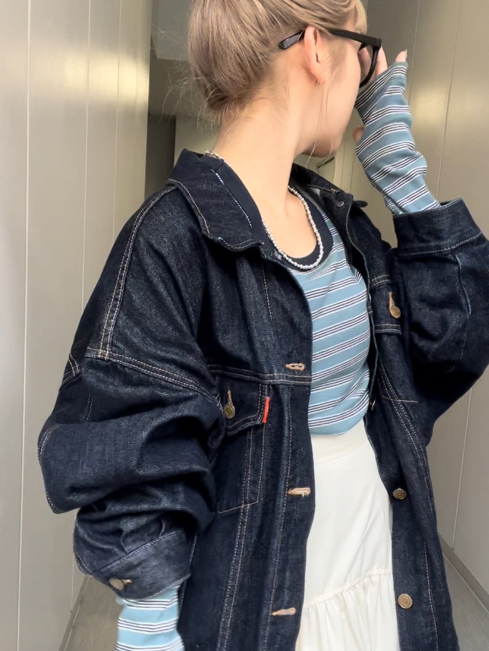 ブルー系のデニムジャケット、ブルー系のTシャツ/カットソー、ホワイト系のスカートを着用したレディースの秋コーディネートの3枚目の写真