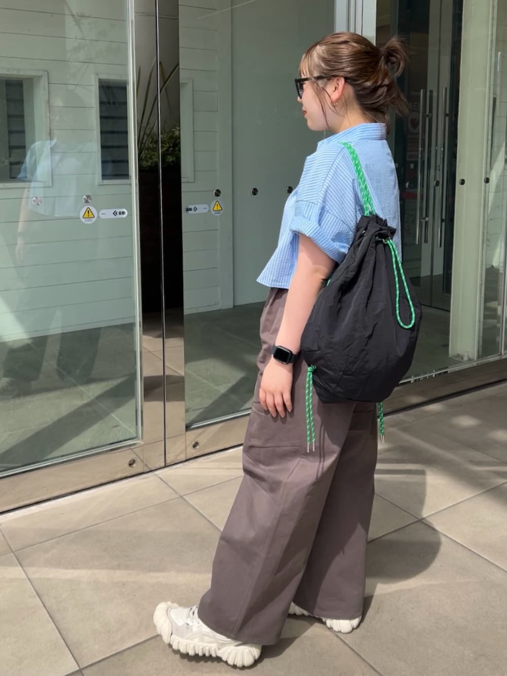 グレー系のチノパンツ、ブルー系のシャツ/ブラウス、ブラック系のバックパック/リュックを着用したレディースの春コーディネートの2枚目の写真