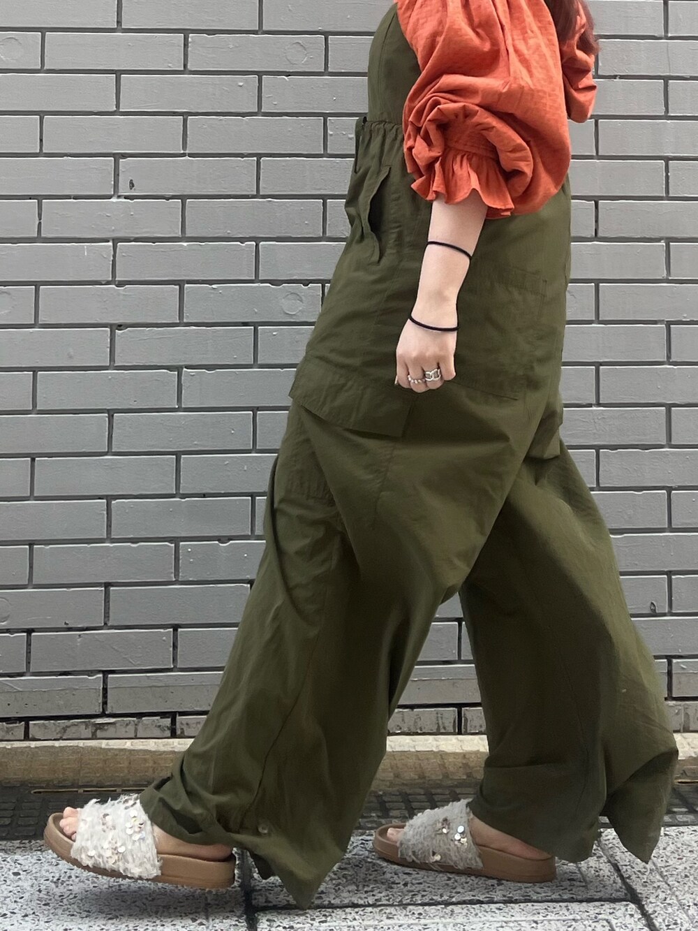 グリーン系のサロペット/オーバーオール、オレンジ系のシャツ/ブラウス、ホワイト系のサンダルを着用したレディースの冬コーディネートの5枚目の写真