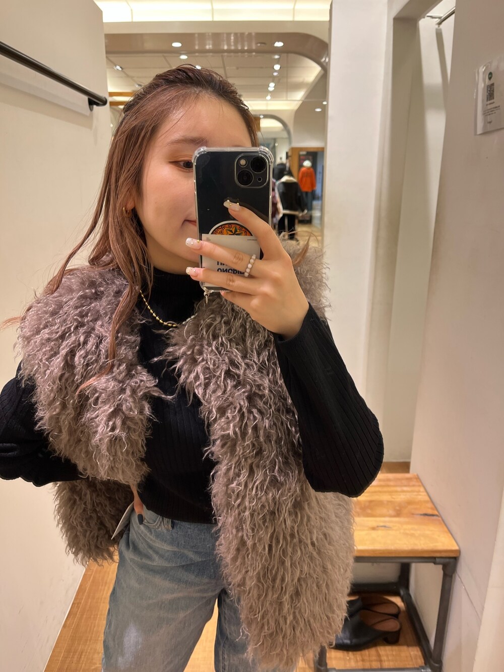 グレー系のベスト、ブルー系のデニムパンツ、ブラック系のニット/セーターを着用したレディースの秋コーディネートの2枚目の写真