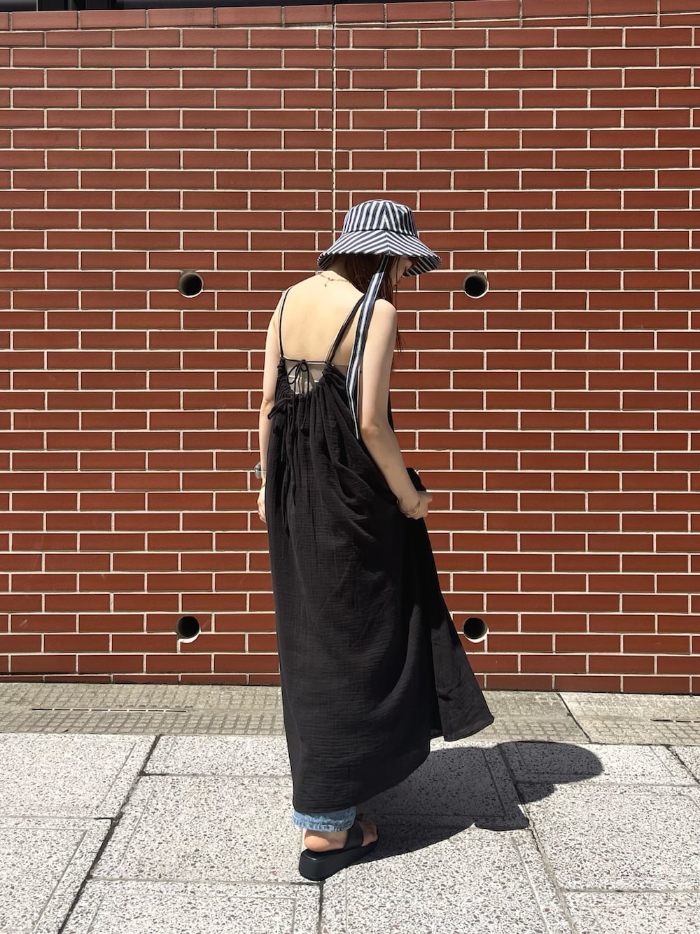 ブラック系のワンピース、ブルー系のデニムパンツ、ベージュ系のキャミソールを着用したレディースの夏コーディネートの2枚目の写真