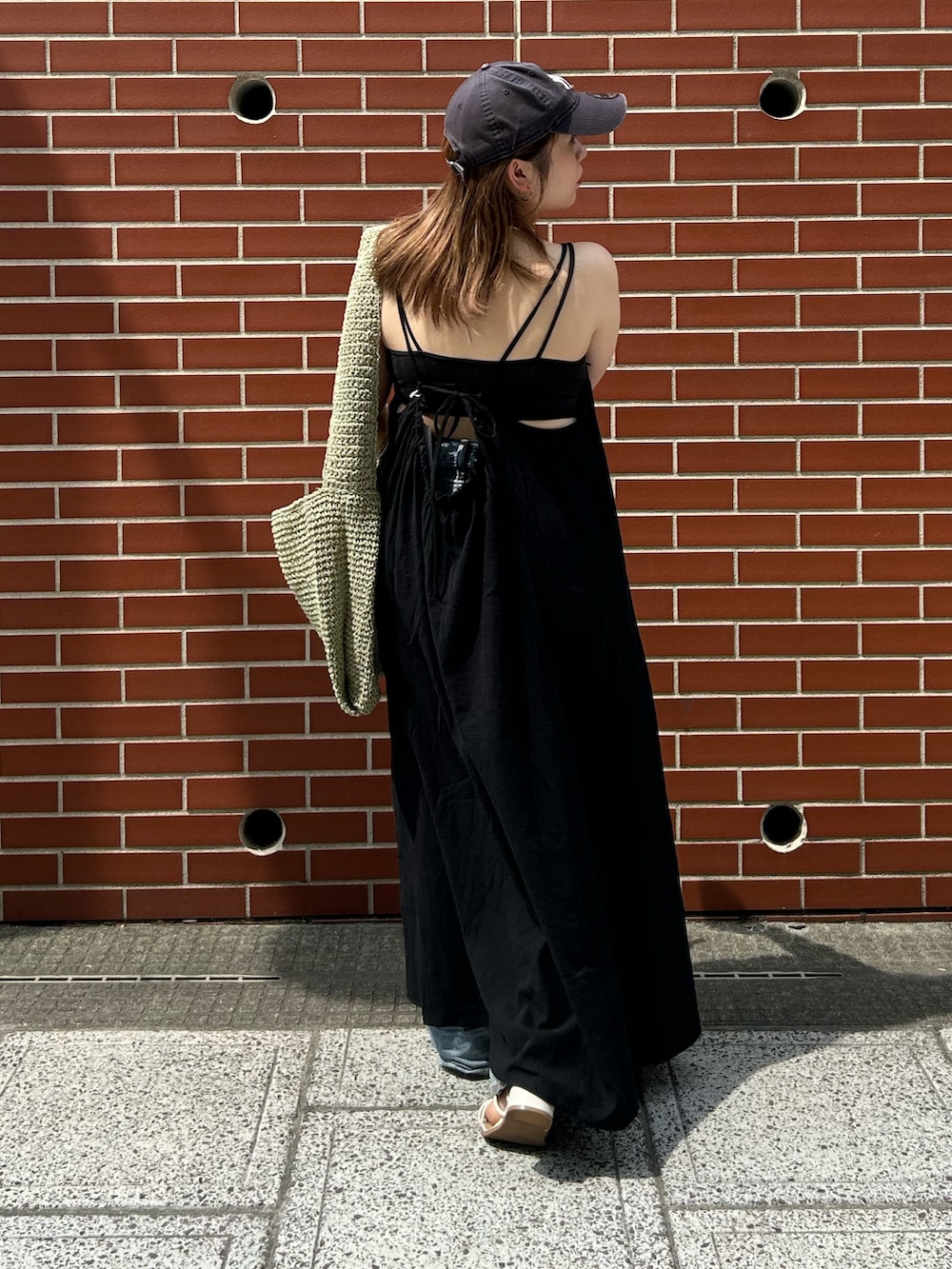 ブルー系のデニムパンツ、ブラック系のワンピース、グリーン系のショルダーバッグを着用したレディースの夏コーディネートの3枚目の写真