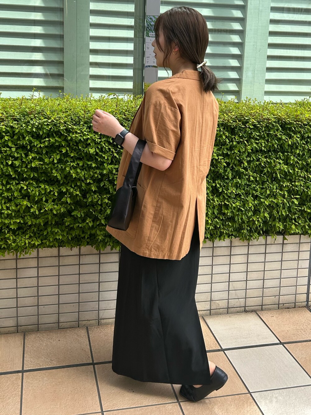 イエロー系のシャツ/ブラウス、ブラック系のハンドバッグ、ブラック系のスカートを着用したレディースの春コーディネートの2枚目の写真