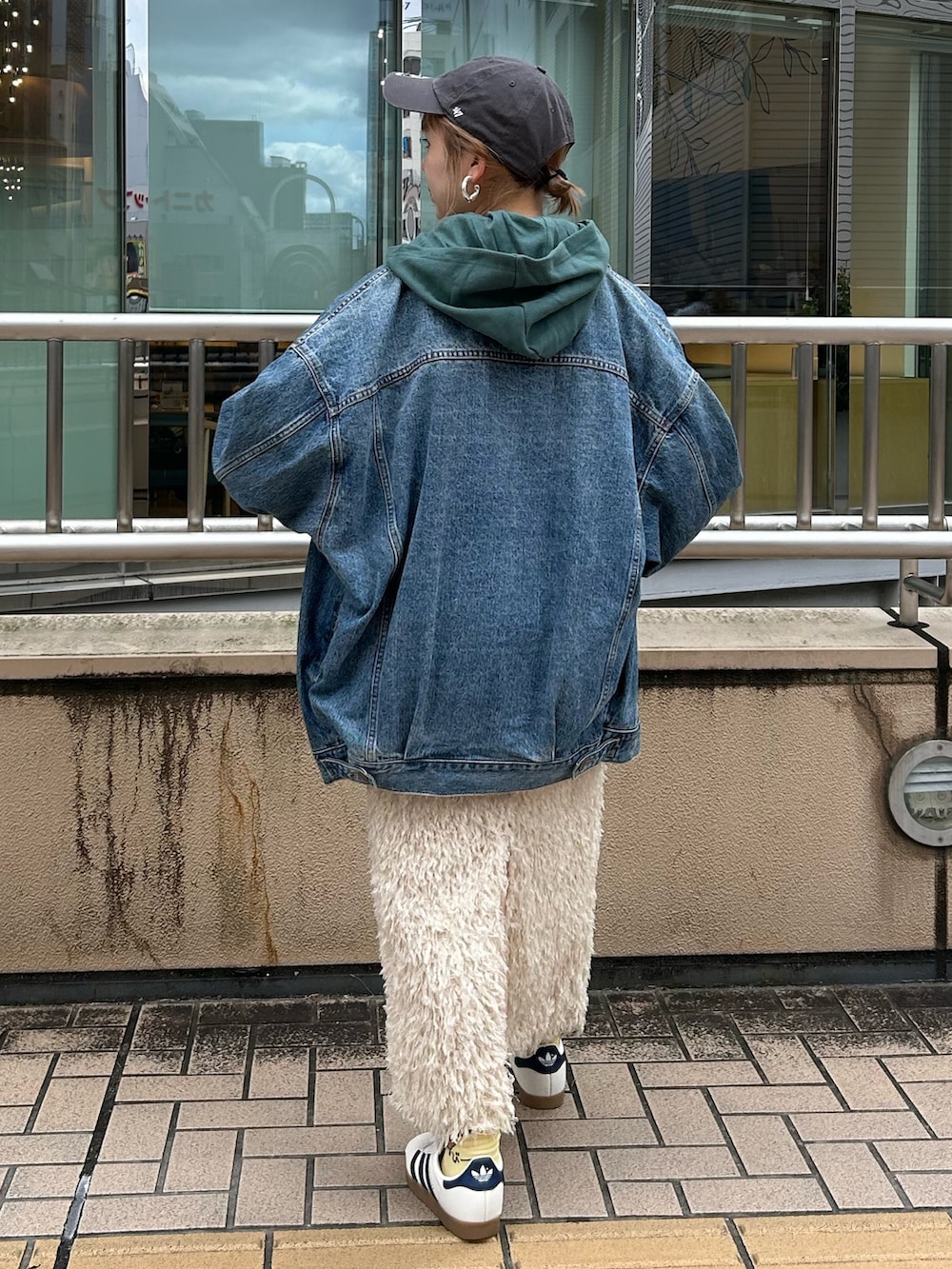グリーン系のパーカー、ホワイト系のスカート、ブルー系のデニムジャケットを着用したレディースの秋コーディネートの3枚目の写真