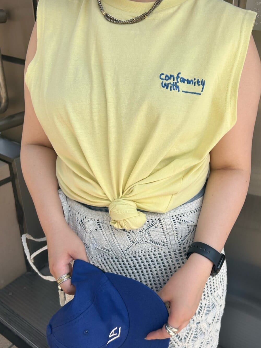 ブルー系のデニムパンツ、イエロー系のタンクトップ、ホワイト系のスカートを着用したレディースの夏コーディネートの4枚目の写真