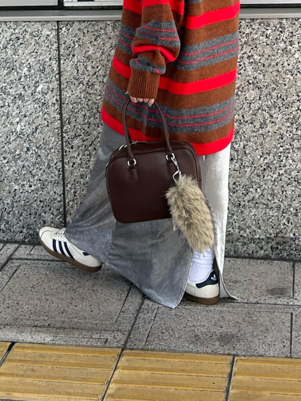 グレー系のスカート、レッド系のニット/セーター、ブラウン系のハンドバッグを着用したレディースの秋コーディネートの6枚目の写真