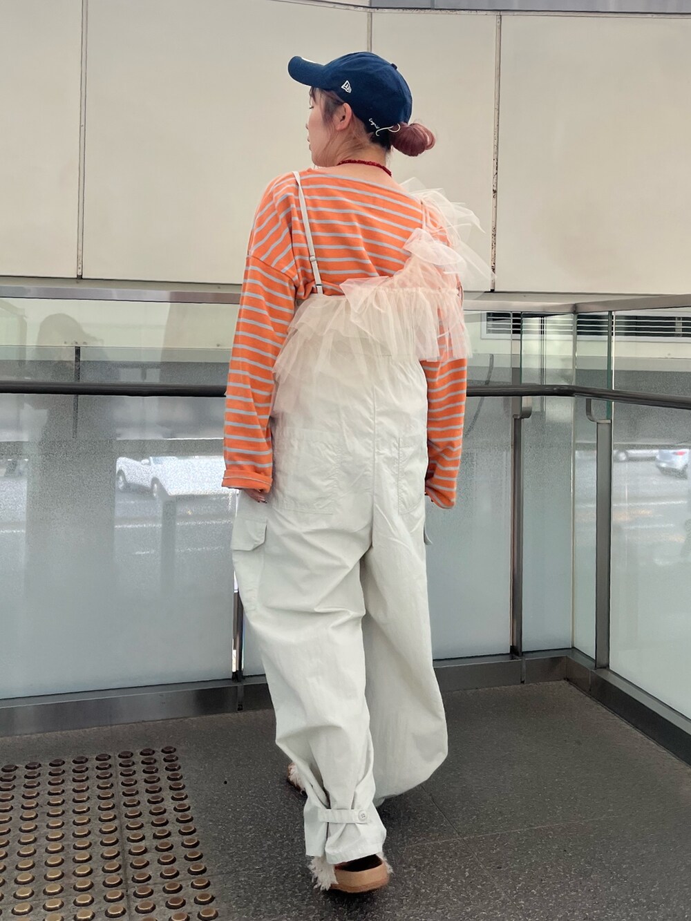 グレー系のサロペット/オーバーオール、ベージュ系のベスト、オレンジ系のTシャツ/カットソーを着用したレディースの冬コーディネートの4枚目の写真