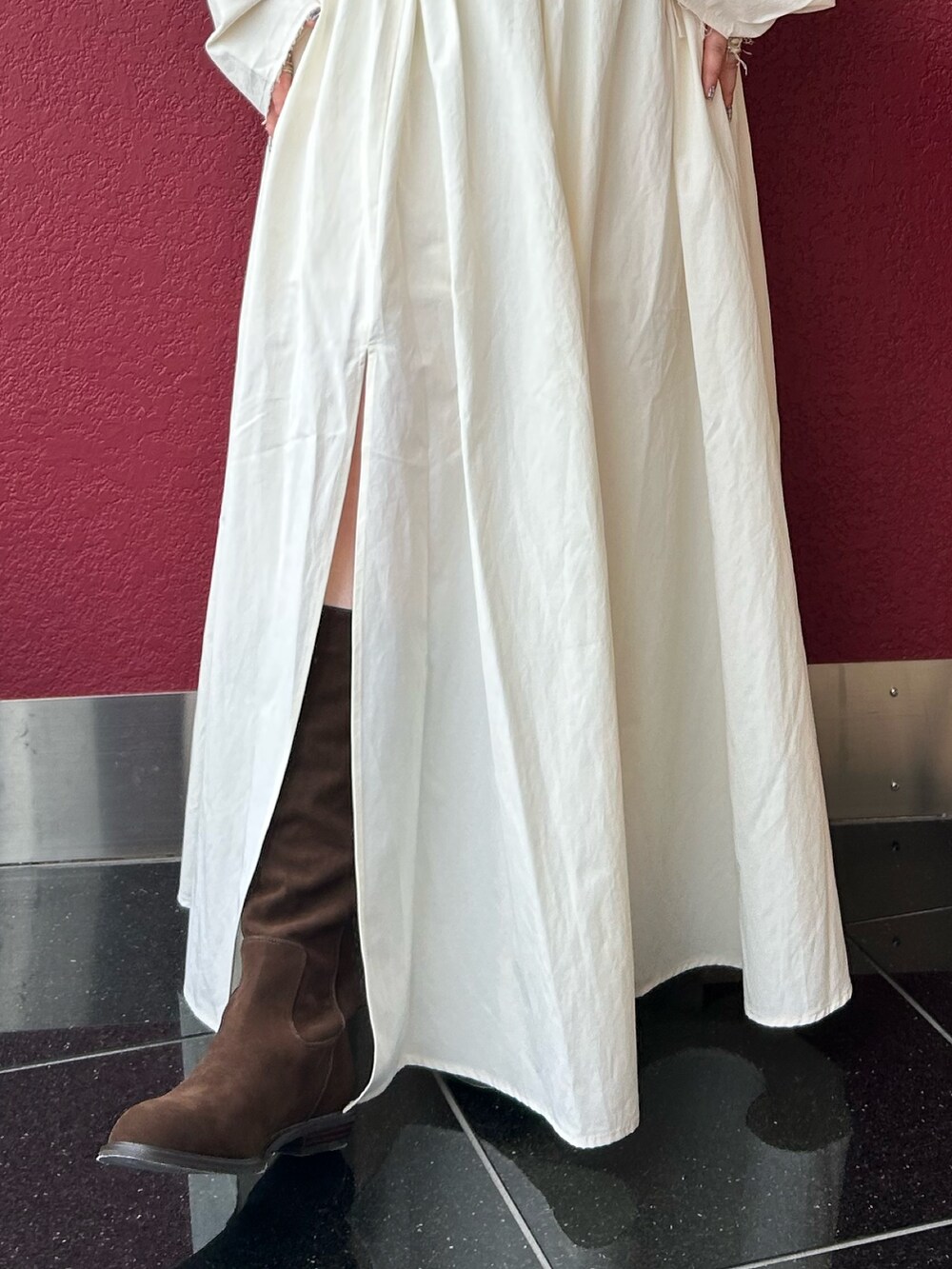 ホワイト系のスカート、ホワイト系のパーカー、ブラウン系のブーツを着用したレディースの秋コーディネートの4枚目の写真