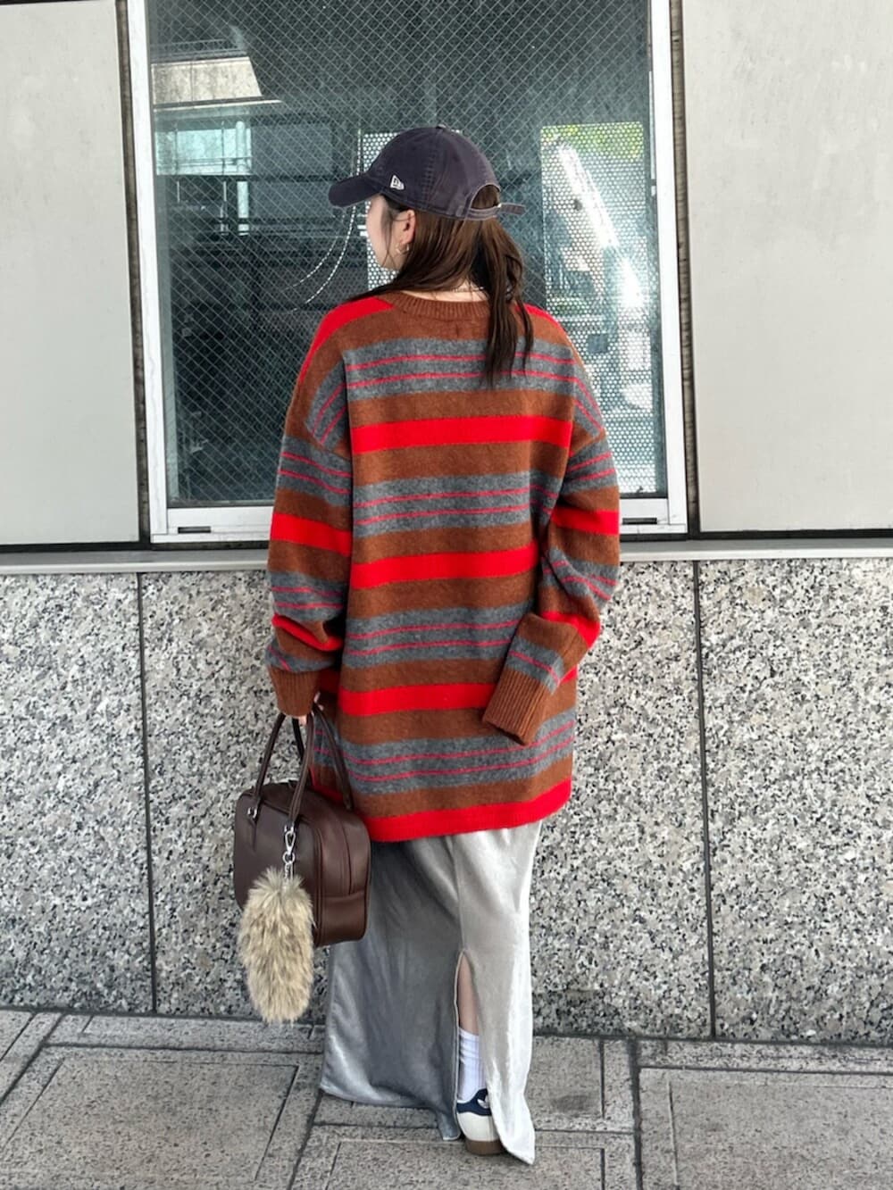 グレー系のスカート、レッド系のニット/セーター、ブラウン系のハンドバッグを着用したレディースの秋コーディネートの3枚目の写真