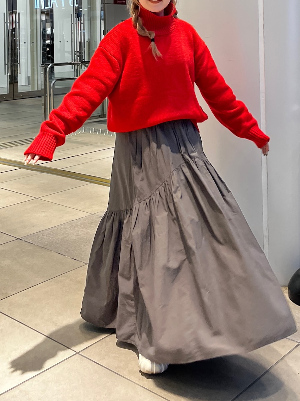 レッド系のニット/セーター、グレー系のスカートを着用したレディースの秋コーディネートの4枚目の写真