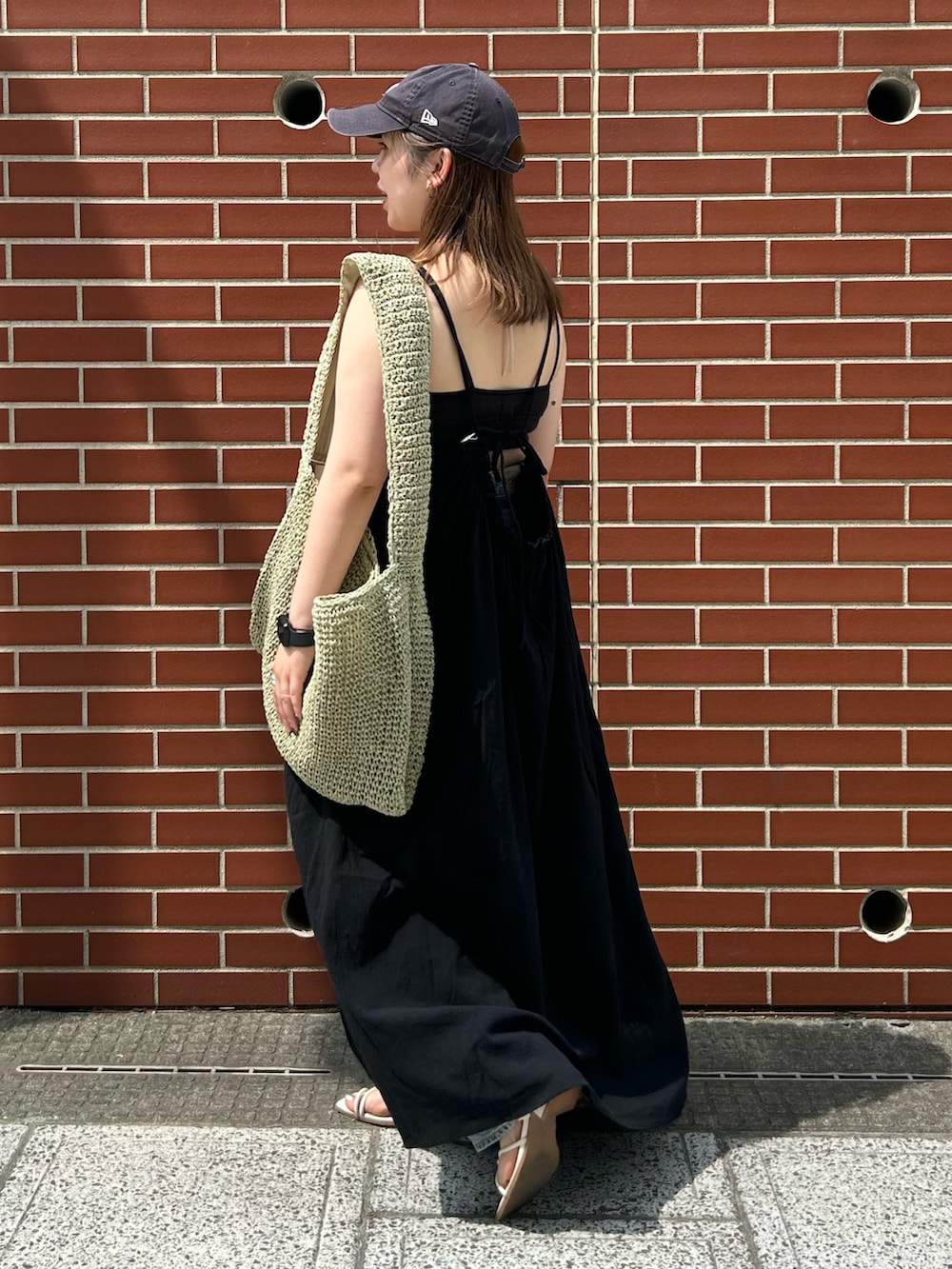 ブルー系のデニムパンツ、ブラック系のワンピース、グリーン系のショルダーバッグを着用したレディースの夏コーディネートの2枚目の写真