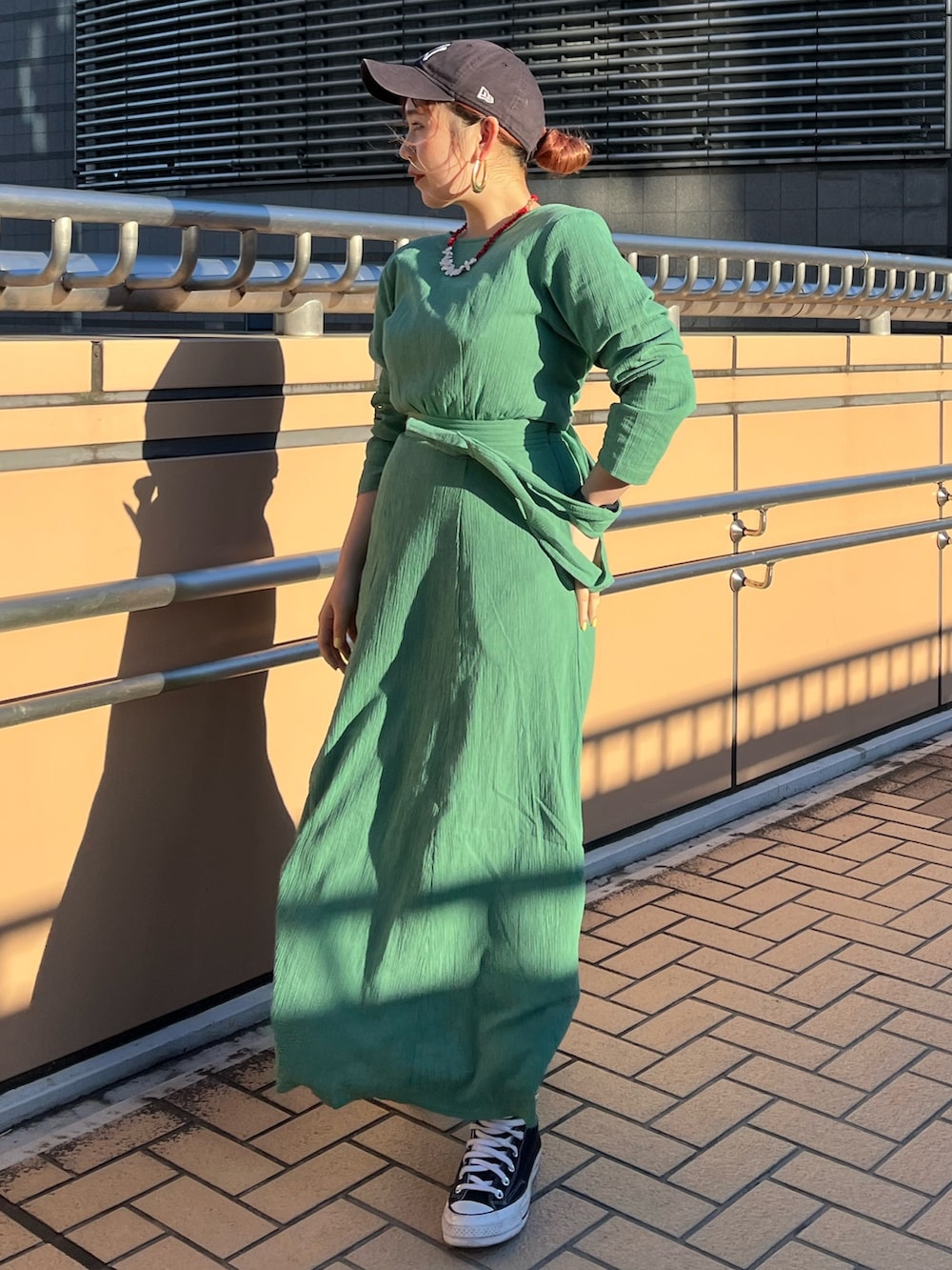 グリーン系のワンピースを着用したレディースの春コーディネートの2枚目の写真