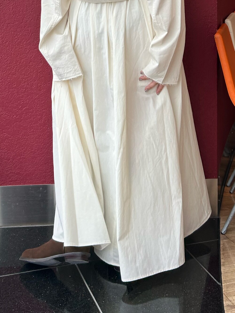 ホワイト系のスカート、ホワイト系のパーカー、ブラウン系のブーツを着用したレディースの秋コーディネートの6枚目の写真