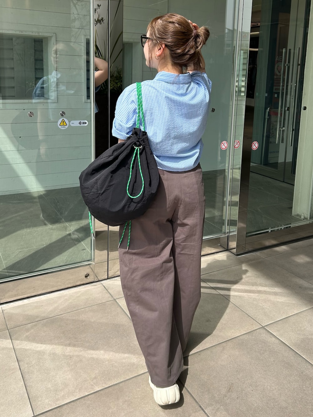 グレー系のチノパンツ、ブルー系のシャツ/ブラウス、ブラック系のバックパック/リュックを着用したレディースの春コーディネートの3枚目の写真