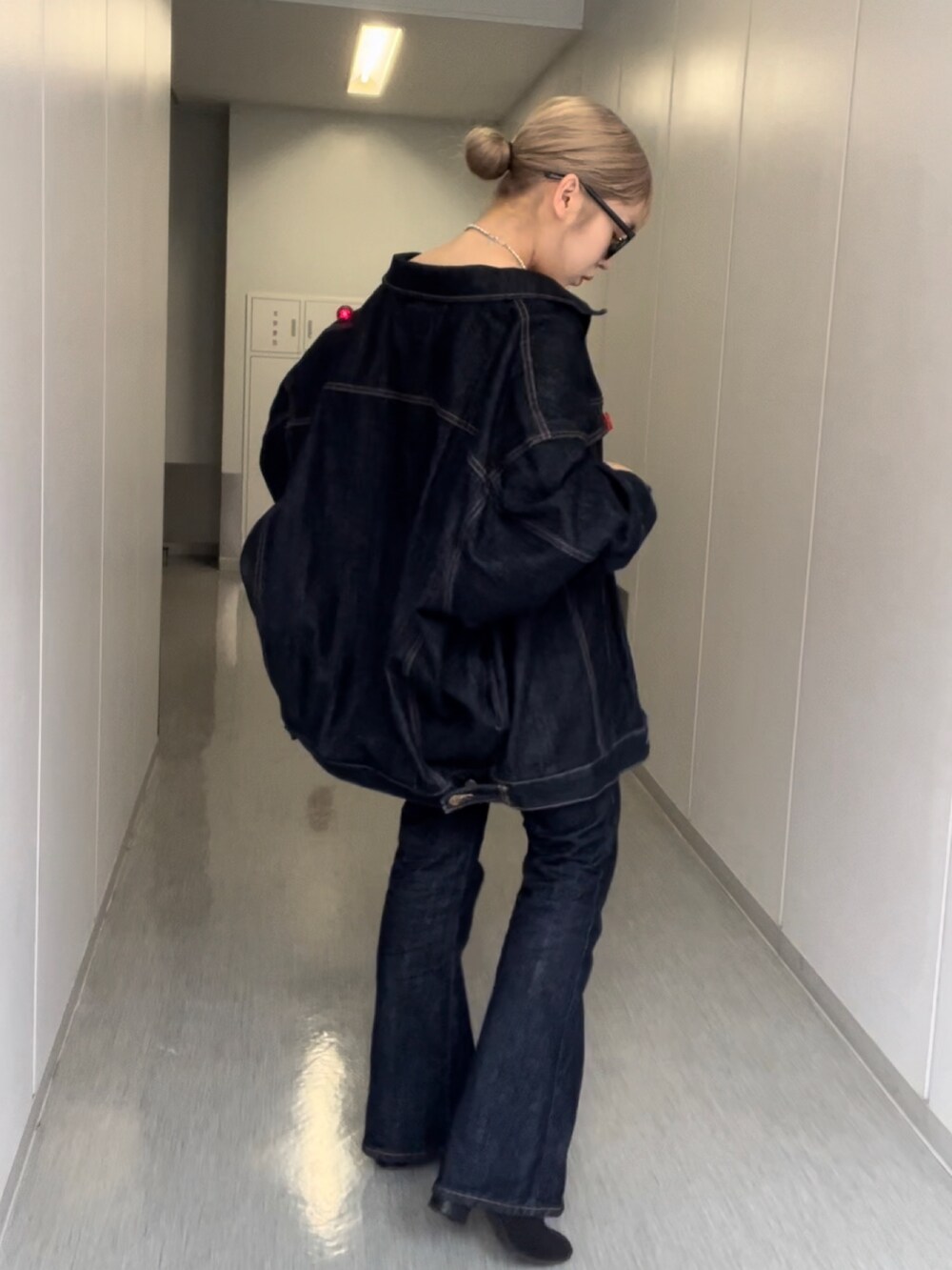 ブルー系のデニムジャケット、ブルー系のデニムパンツ、シルバー系のネックレスを着用したレディースの秋コーディネートの2枚目の写真