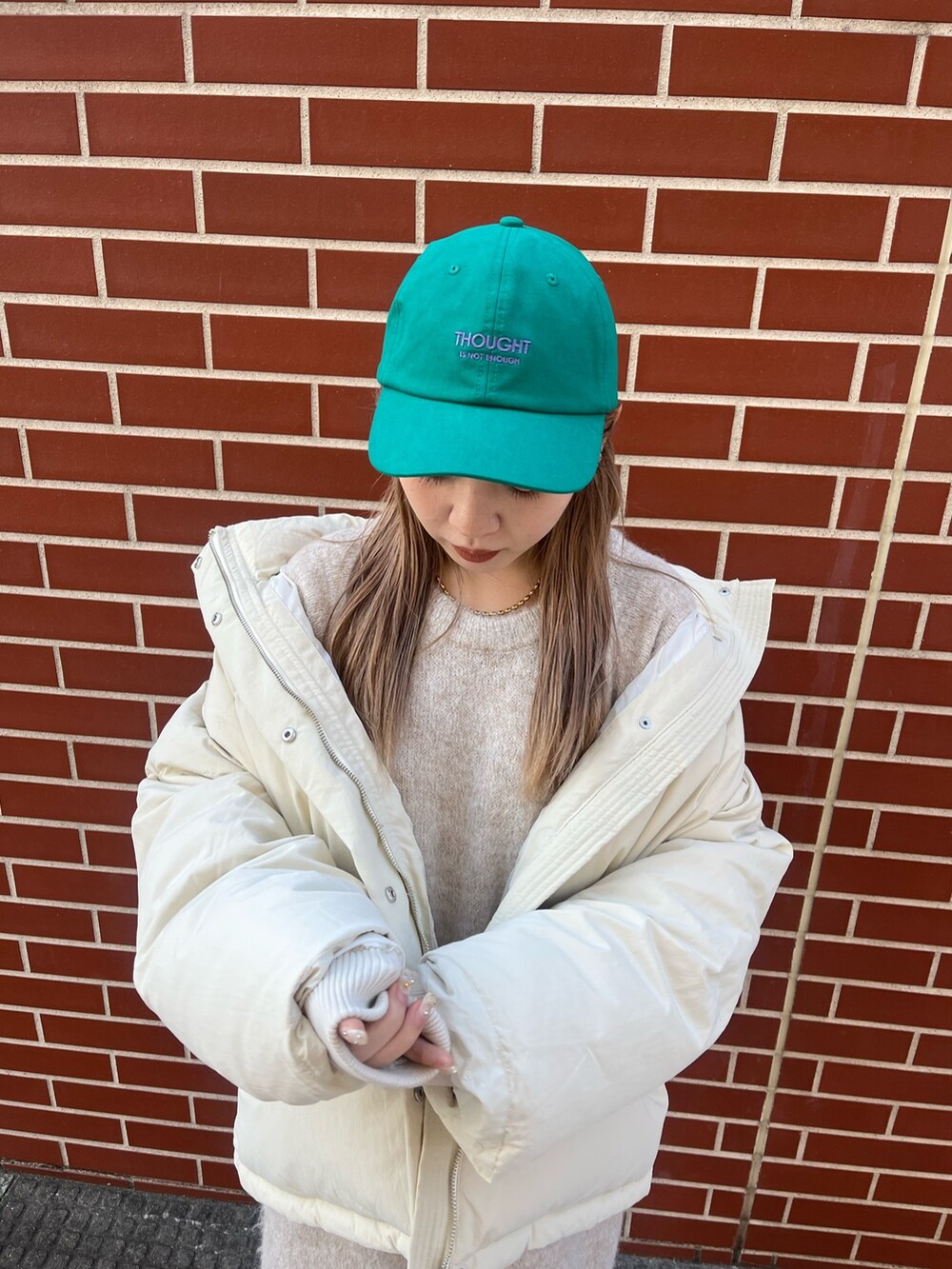 ホワイト系のワンピース、ホワイト系のダウンジャケット/コート、グリーン系のキャップを着用したレディースの秋コーディネートの7枚目の写真