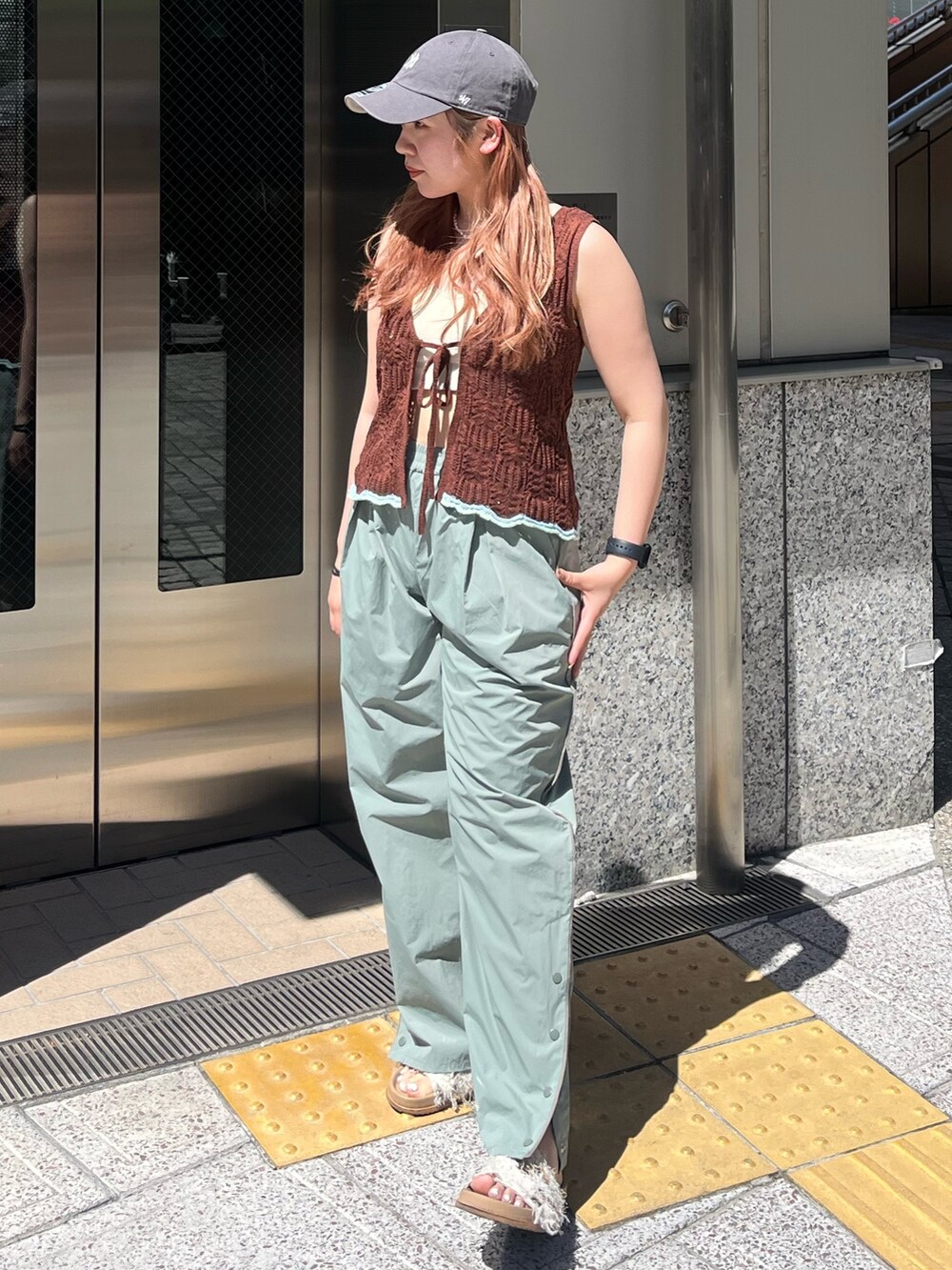 グリーン系のその他パンツ、ブラウン系のニット/セーター、ホワイト系のキャミソールを着用したレディースの春コーディネートの2枚目の写真