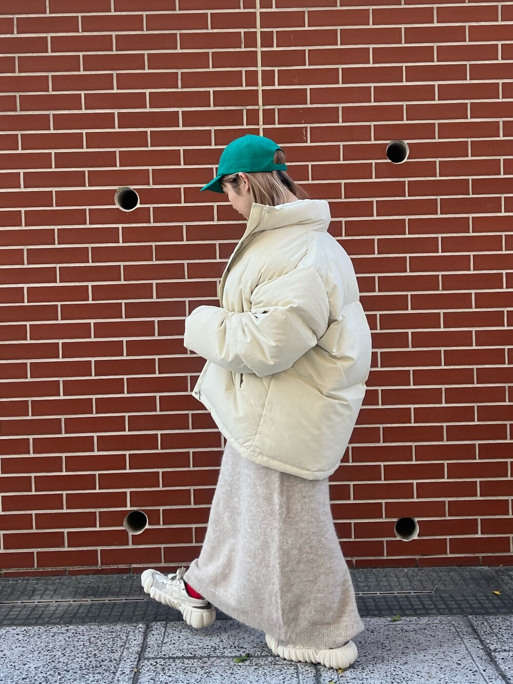 ホワイト系のワンピース、ホワイト系のダウンジャケット/コート、グリーン系のキャップを着用したレディースの秋コーディネートの4枚目の写真