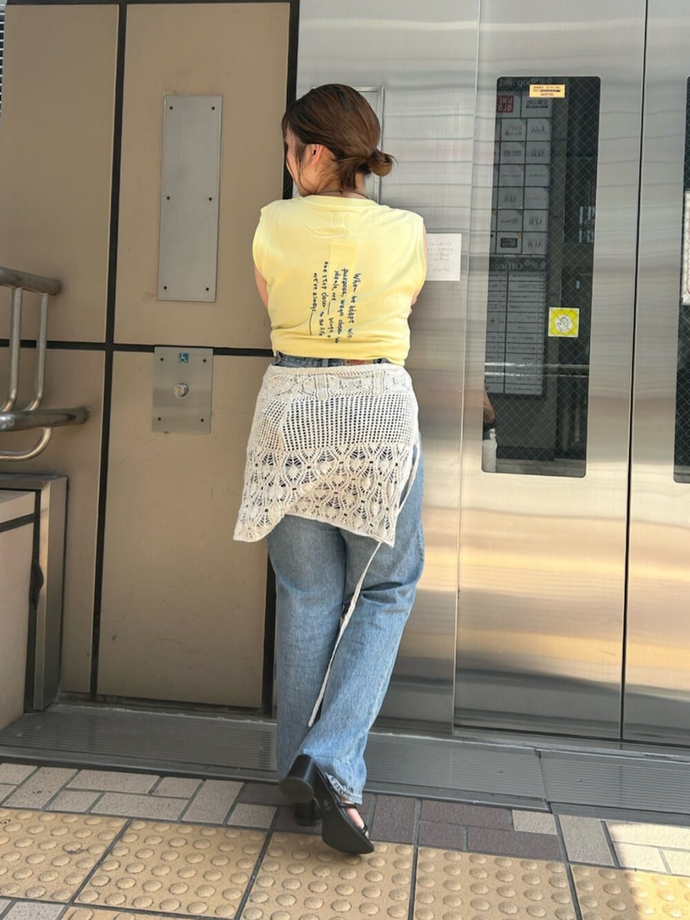 ブルー系のデニムパンツ、イエロー系のタンクトップ、ホワイト系のスカートを着用したレディースの夏コーディネートの3枚目の写真