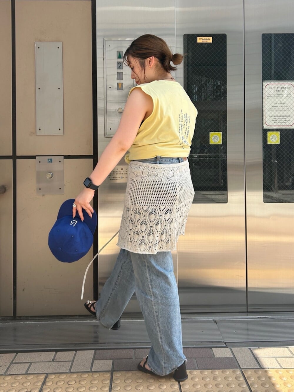 ブルー系のデニムパンツ、イエロー系のタンクトップ、ホワイト系のスカートを着用したレディースの夏コーディネートの2枚目の写真