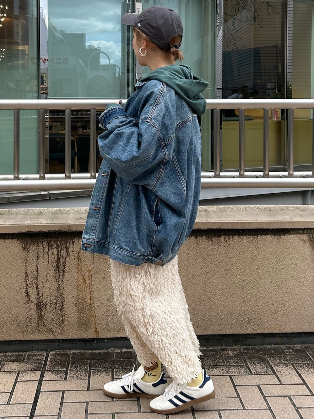 グリーン系のパーカー、ホワイト系のスカート、ブルー系のデニムジャケットを着用したレディースの秋コーディネートの2枚目の写真