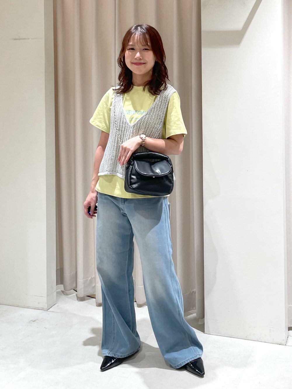ブルー系のデニムパンツ、ブラック系のパンプス、ブラック系のショルダーバッグを着用したレディースの夏コーディネートの3枚目の写真