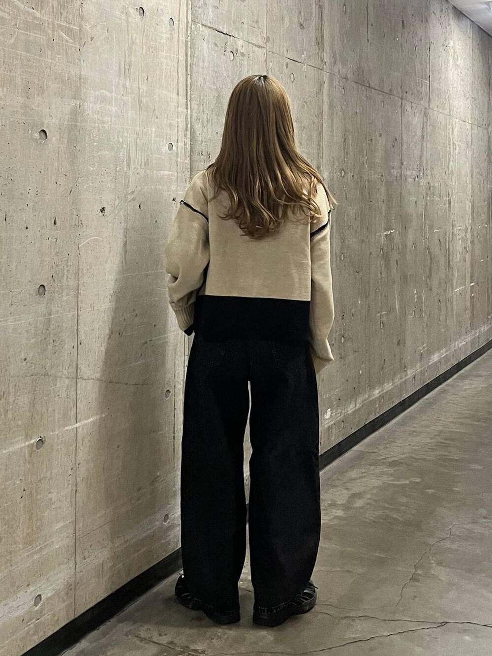 ベージュ系のニット/セーター、ブラック系のデニムパンツを着用したレディースの秋コーディネートの5枚目の写真