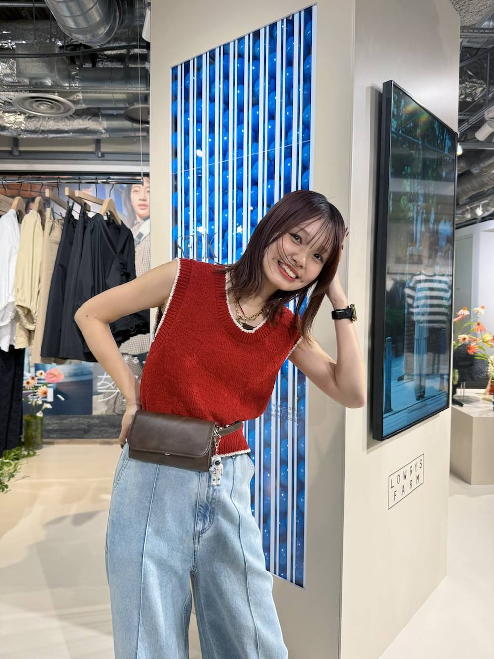 ブルー系のデニムパンツ、ブラック系のサンダル、レッド系のベストを着用したレディースの春コーディネートの3枚目の写真