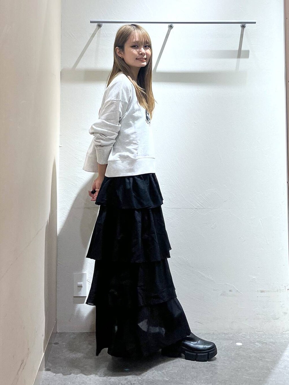 グレー系のスウェット、ブラック系のスカートを着用したレディースの秋コーディネートの2枚目の写真