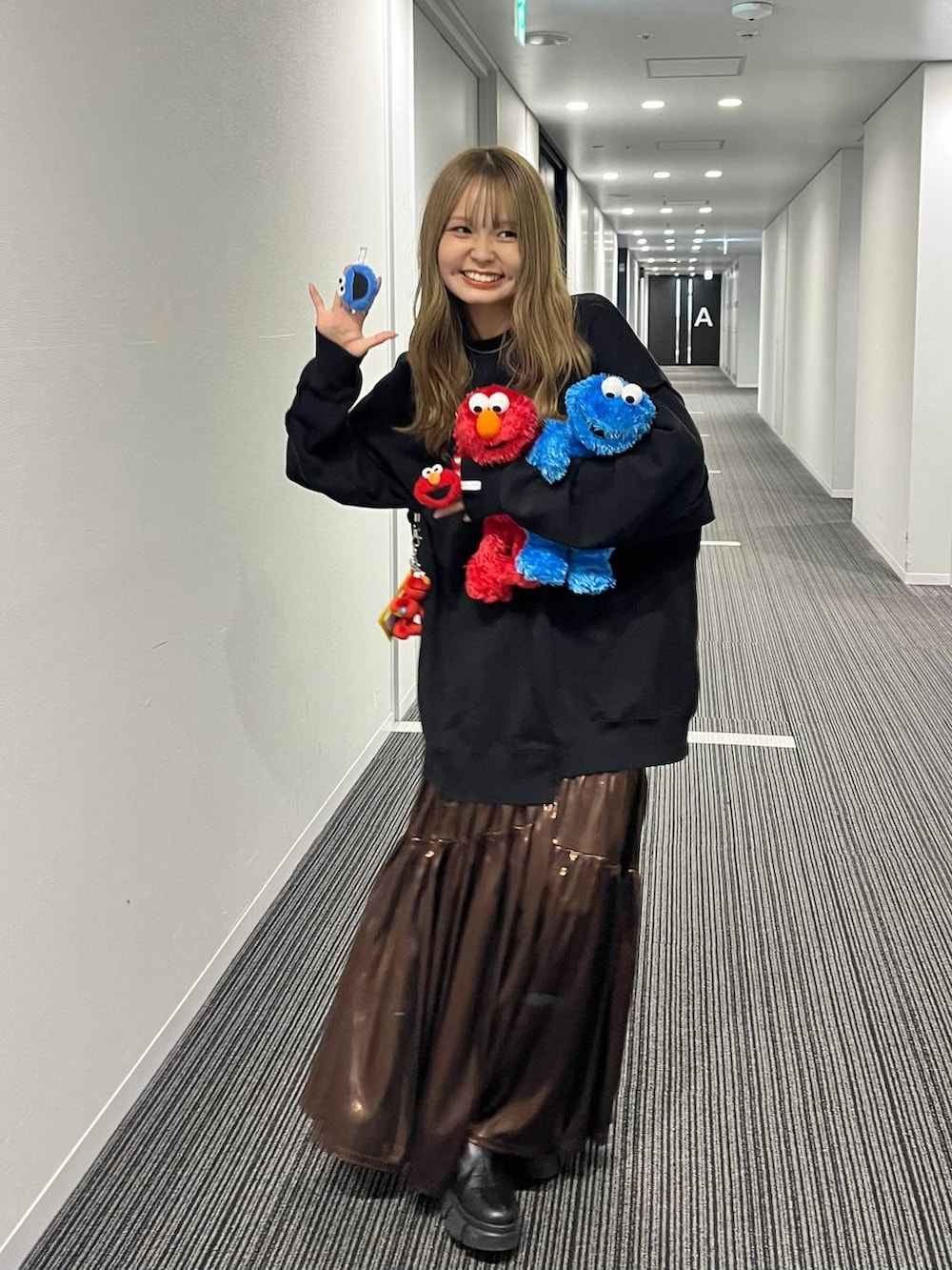 ブラウン系のスカート、グレー系のスウェット、レッド系のその他雑貨を着用したレディースの秋コーディネートの2枚目の写真