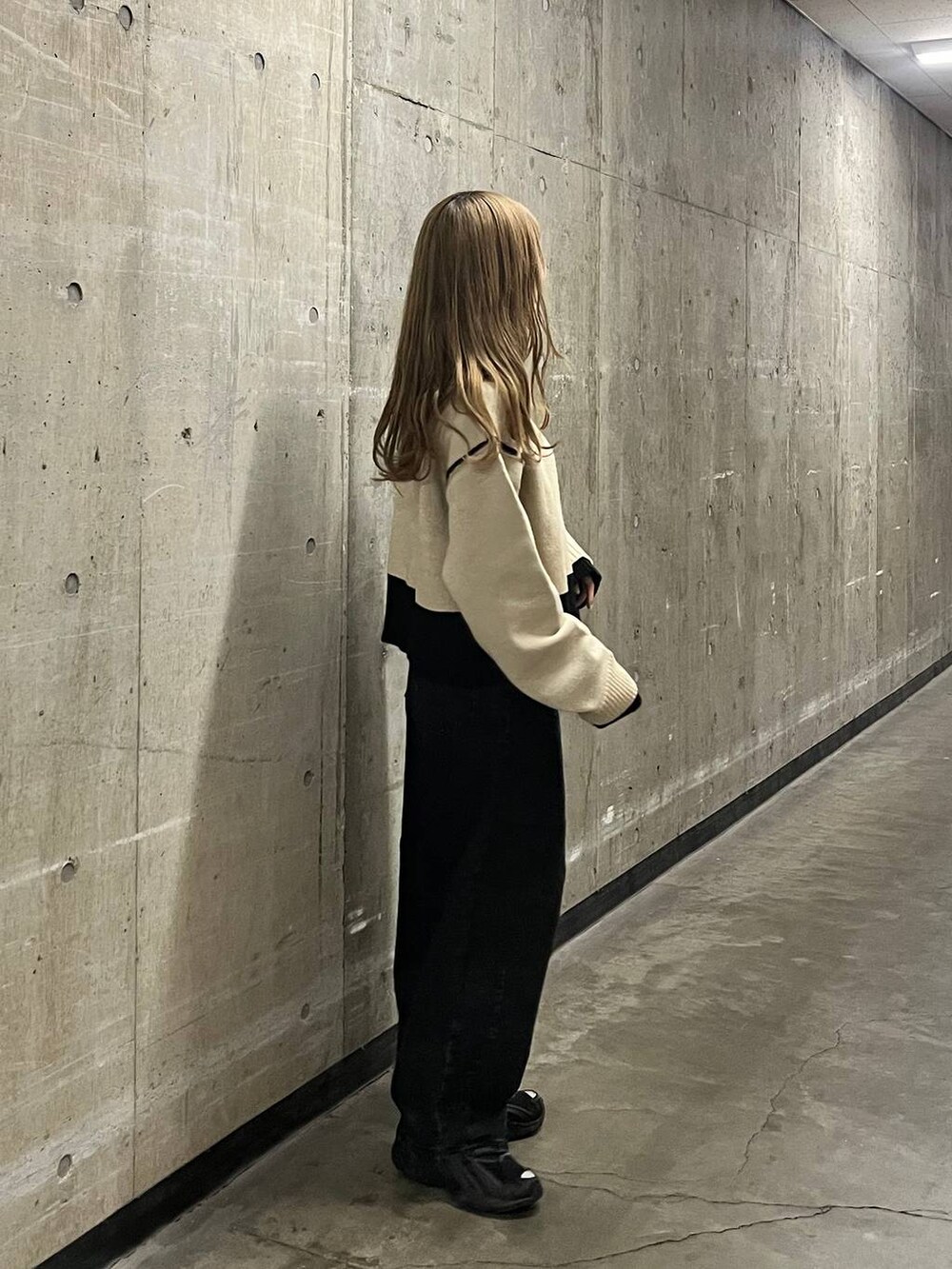 ベージュ系のニット/セーター、ブラック系のデニムパンツを着用したレディースの秋コーディネートの4枚目の写真