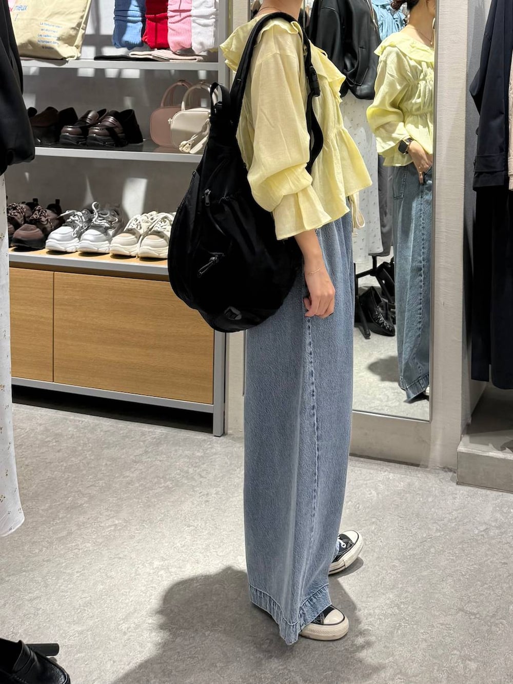 ブルー系のデニムパンツ、ブラック系のショルダーバッグ、イエロー系のシャツ/ブラウスを着用したレディースの春コーディネートの3枚目の写真