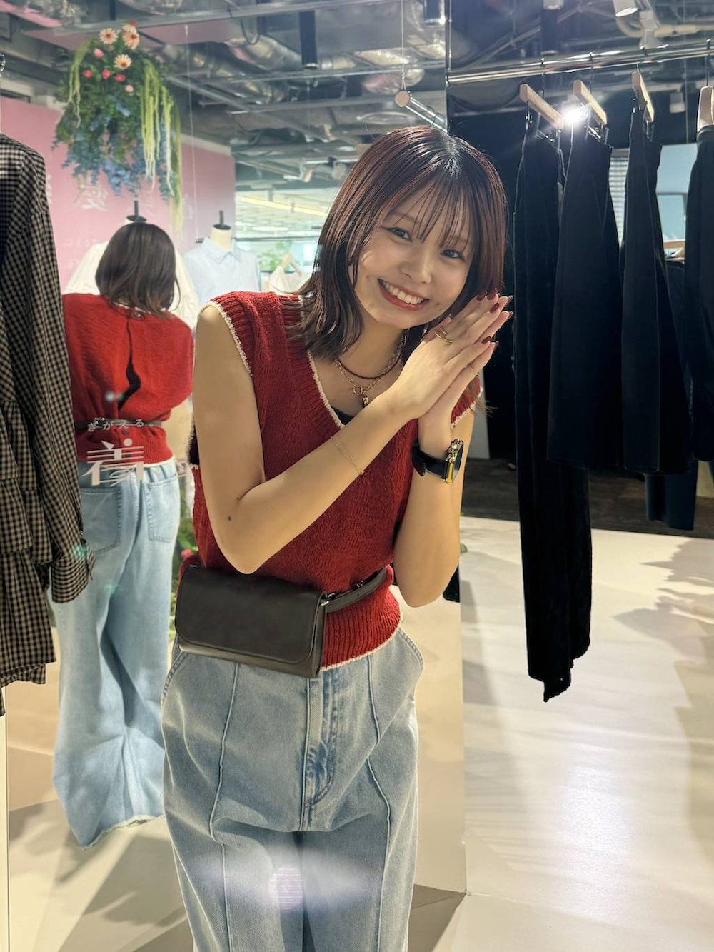 ブルー系のデニムパンツ、ブラック系のサンダル、レッド系のベストを着用したレディースの春コーディネートの4枚目の写真