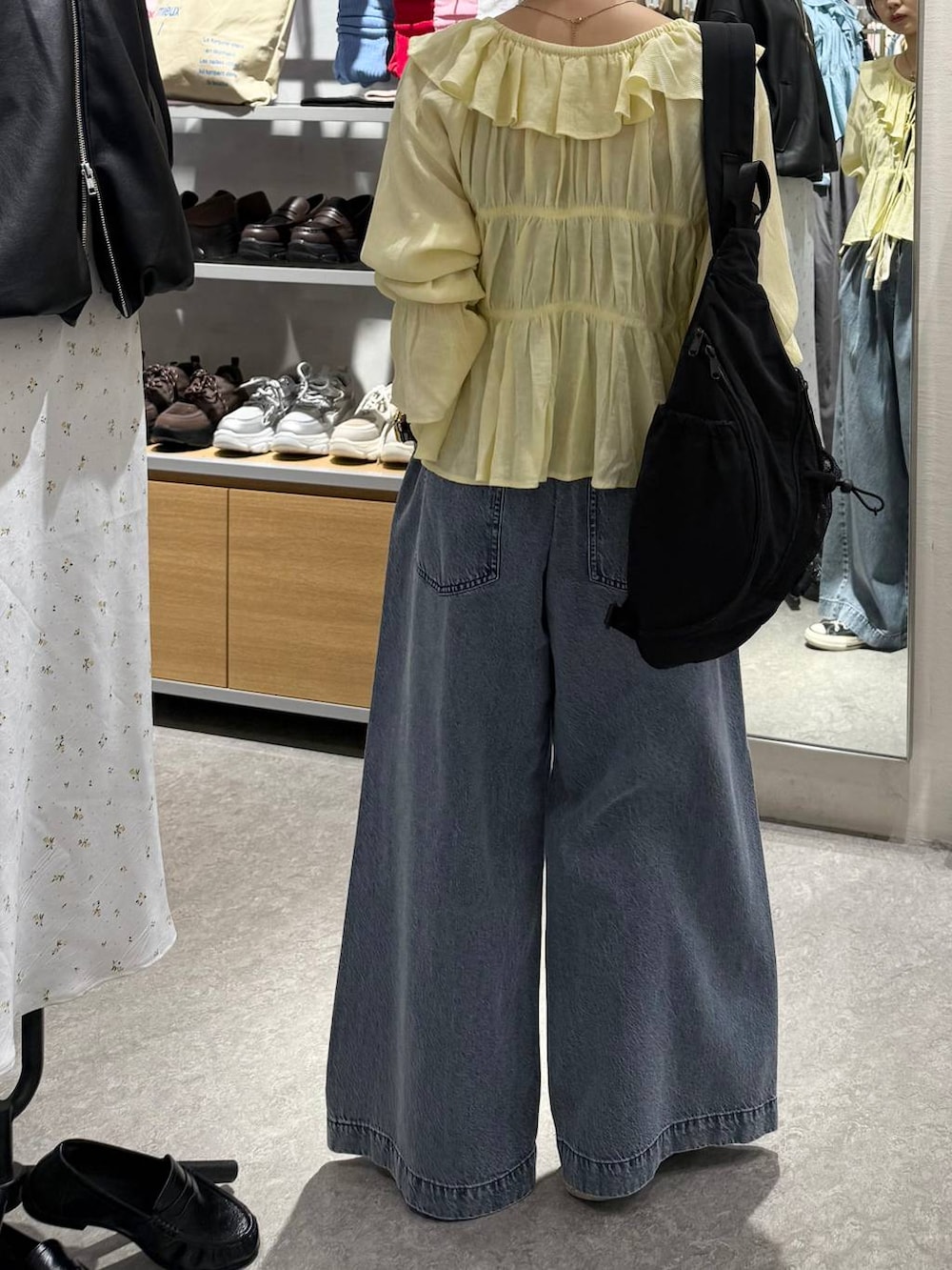 ブルー系のデニムパンツ、ブラック系のショルダーバッグ、イエロー系のシャツ/ブラウスを着用したレディースの春コーディネートの4枚目の写真