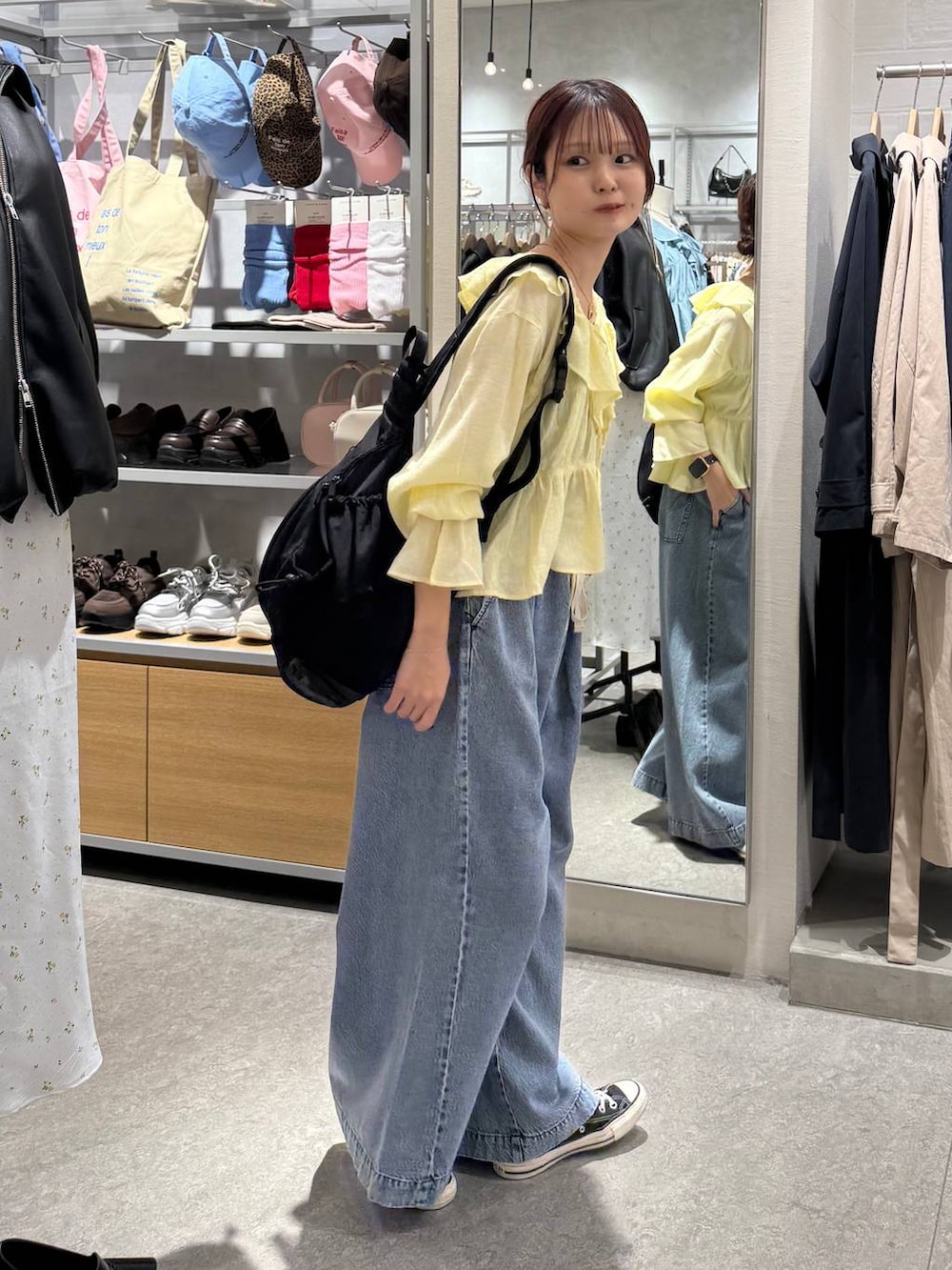 ブルー系のデニムパンツ、ブラック系のショルダーバッグ、イエロー系のシャツ/ブラウスを着用したレディースの春コーディネートの2枚目の写真