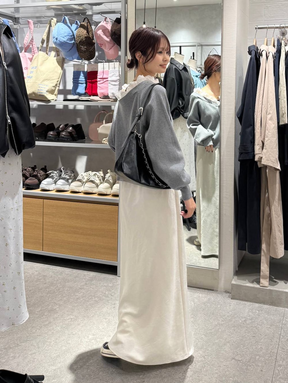 ホワイト系のスカート、ブラック系のショルダーバッグ、グレー系のカーディガン/ボレロを着用したレディースの春コーディネートの2枚目の写真