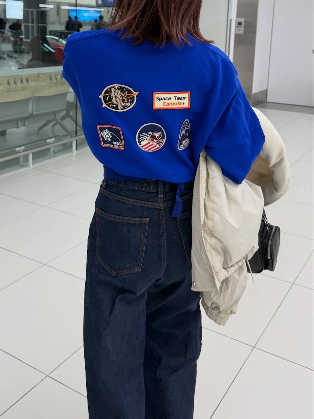 ホワイト系のその他アウター、ブルー系のスウェット、ブラック系のボストンバッグを着用したレディースの冬コーディネートの5枚目の写真