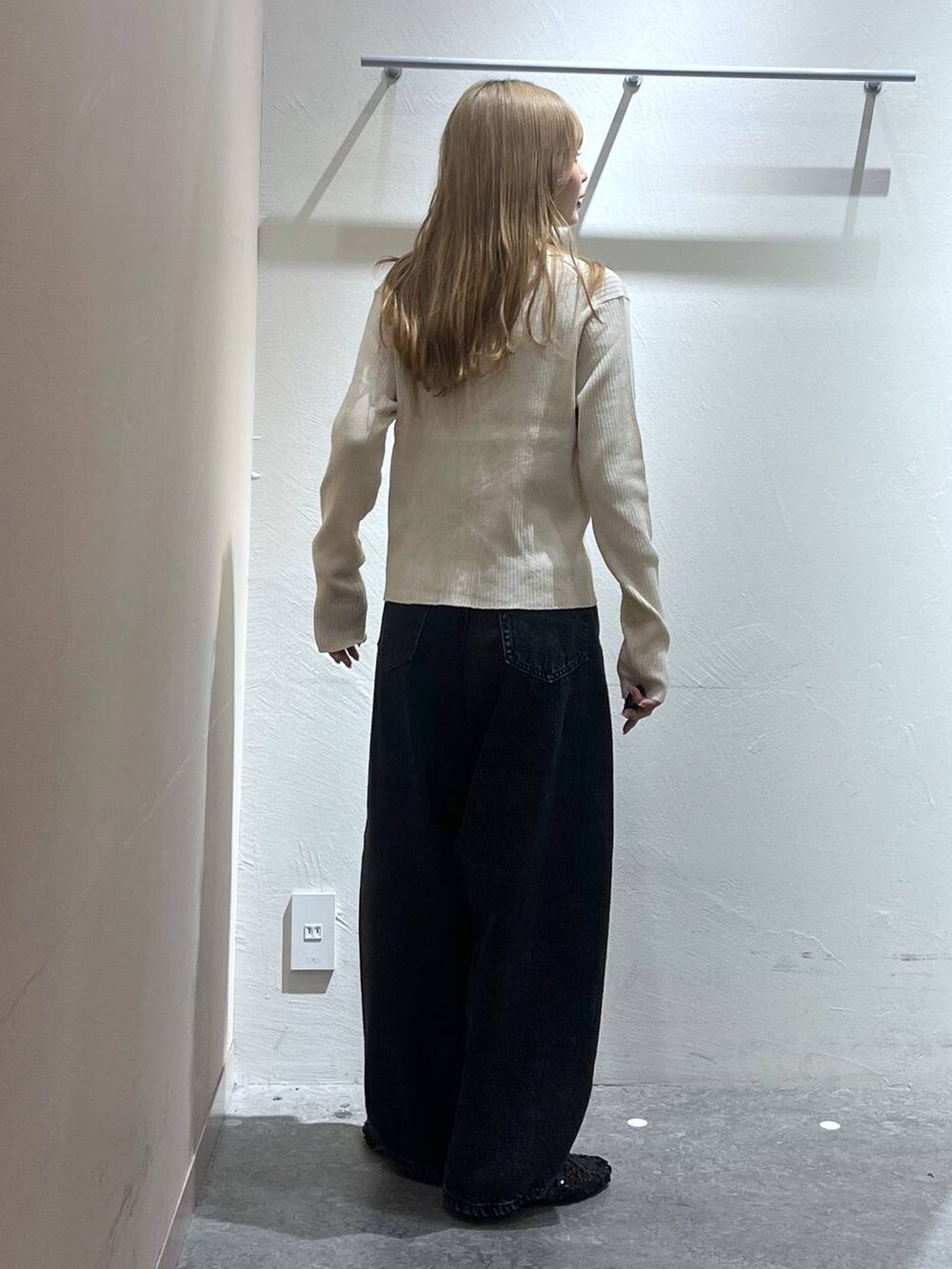 ブラック系のデニムパンツ、ベージュ系のニット/セーター、ブラック系のキャミソールを着用したレディースの秋コーディネートの2枚目の写真