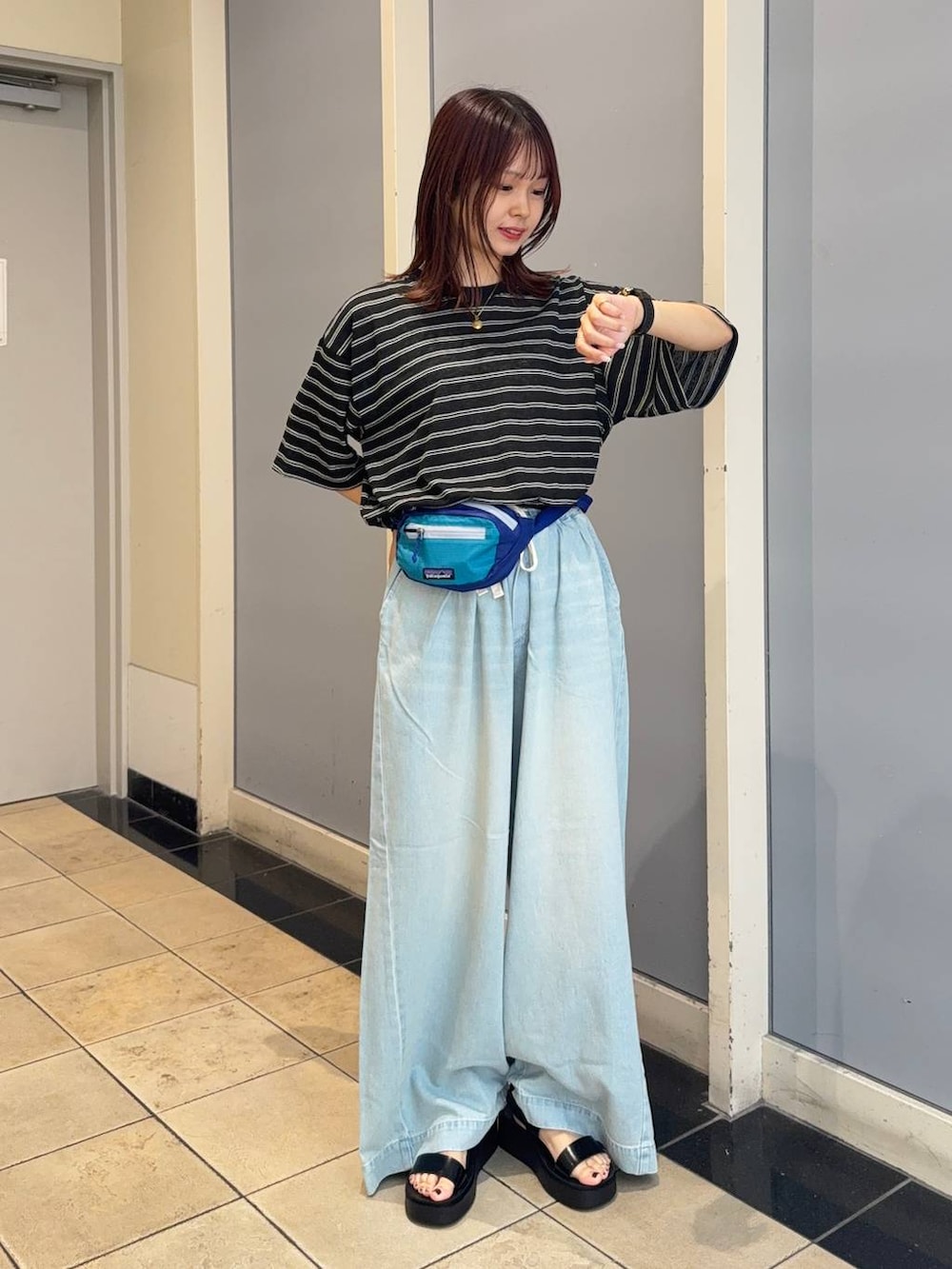 ブラック系のサンダル、ブルー系のデニムパンツ、ブラック系のTシャツ/カットソーを着用したレディースの夏コーディネートの2枚目の写真
